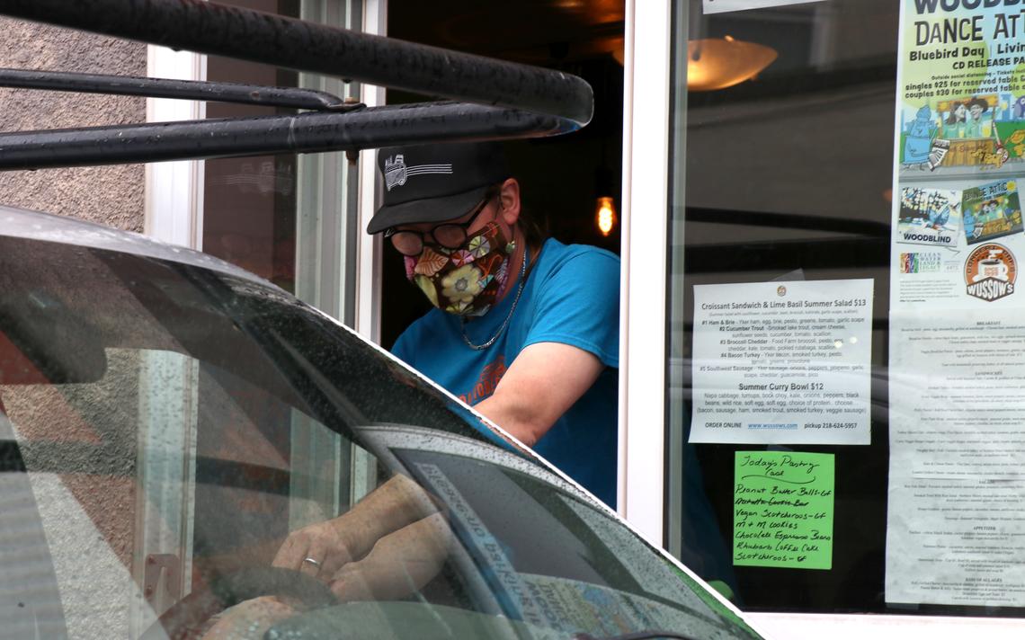 Wussow's Concert Cafe owner Jason Wussow exchanges money with a customer outside the West Duluth cafe's new drive-thru window. Wussow said he will continue to keep the inside of the cafe closed to dine-in customers. (Samantha Erkkila/serkkila@duluthnews.com)