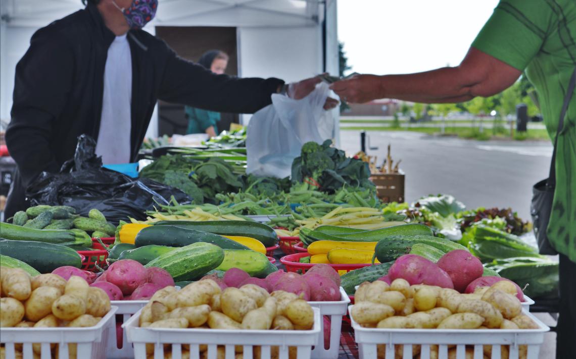 Leng Yang makes a transaction at the vendor tent that his entire family sells produce from each week at the Rochester Farmers Market. (Noah Fish / Agweek)