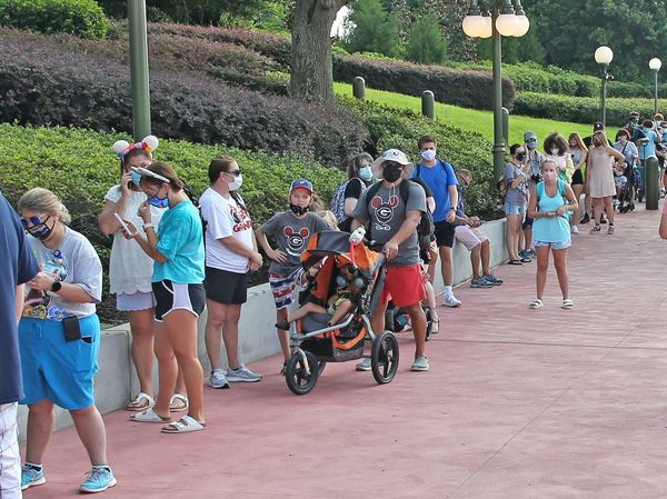 Guests wearing protective masks wait to pick up their tickets at the Magic Kingdom park. Reservations are required as well as masks and temperature checks prior to entering the park.