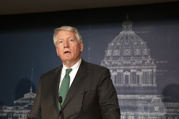 A man in a suit and tie speaks at a podium.