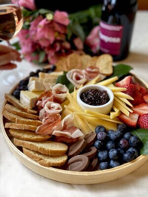 A charcuterie plate of fruit, meats, and cheeses.