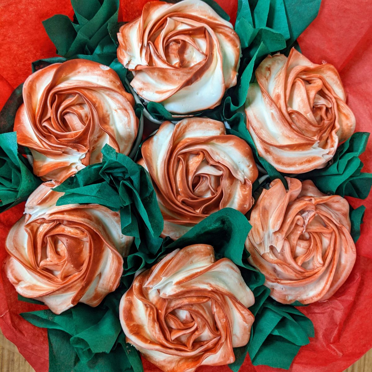Seven cupcakes in a circle decorated to look like roses.