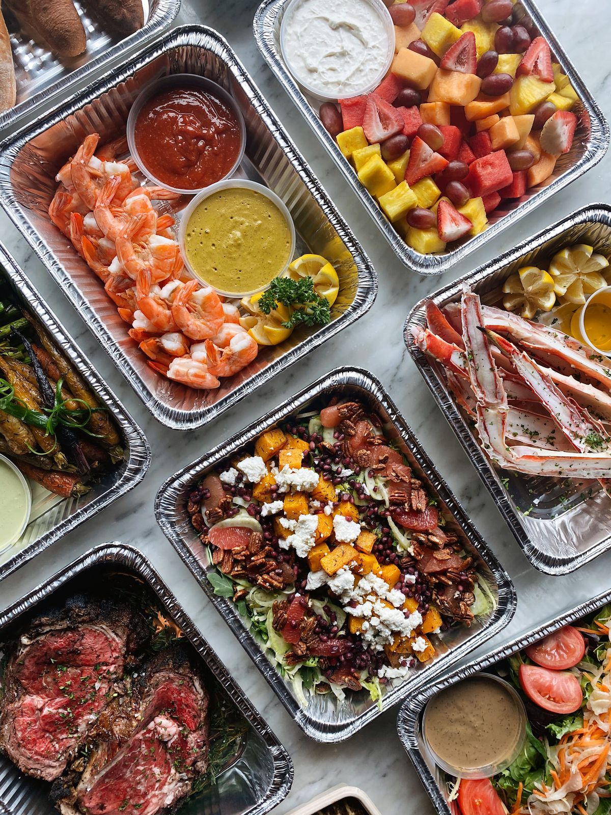 6Smith’s Easter take-and-make meals all portioned in aluminum takeout containers. Prime-rib, salad, shrimp cocktail, fruit salad, and crab legs are pictured.