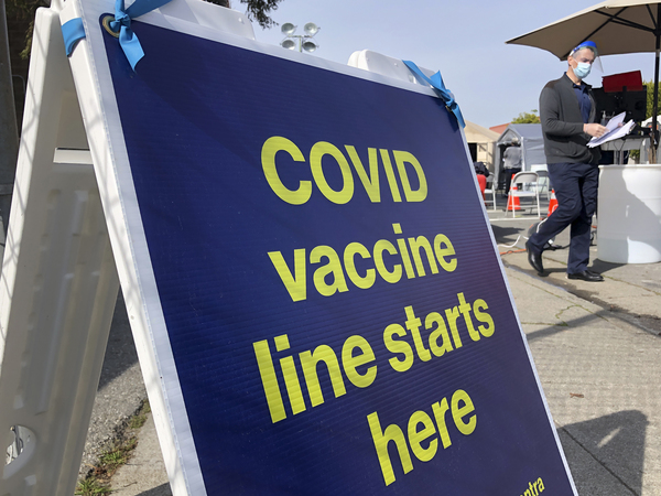A sign is shown at a COVID-19 vaccine site in San Francisco on Feb. 8. The rollout of vaccines is raising the prospect of increased travel and spending by Americans.