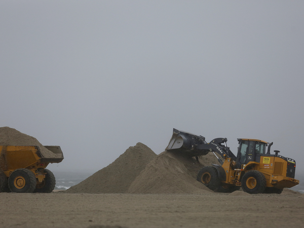 A front-end loader and dump truck move beach sand to protect vulnerable areas from flooding in in Southern California.