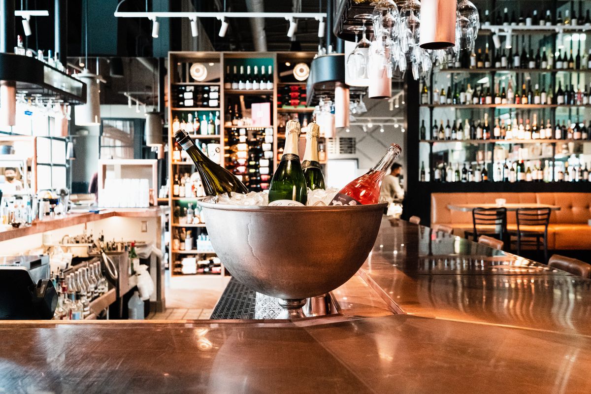 A giant silver bowl on the copper bar filled with ice and bottles of wine