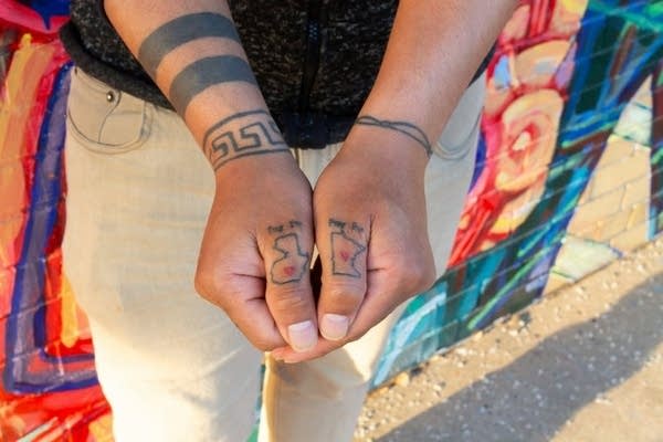 A close-up of tattoos on a person's thumbs. 
