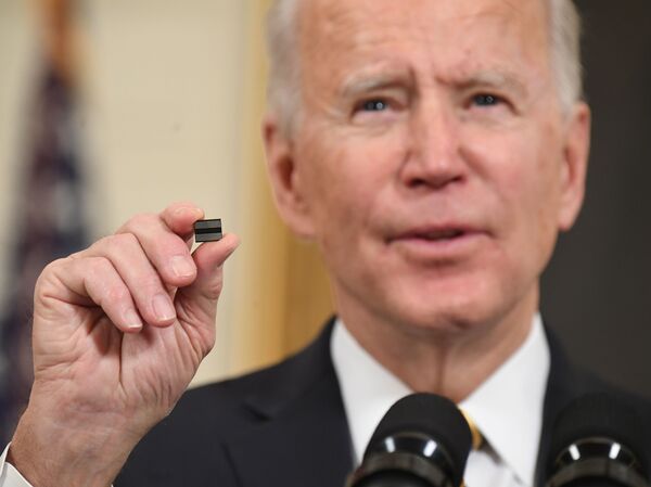 President Biden holds a microchip as he speaks before signing an executive order on securing critical supply chains at the White House in Washington, D.C., on Feb. 24. A shortage of chips after a surge in demand hampered key sectors such as car makers.