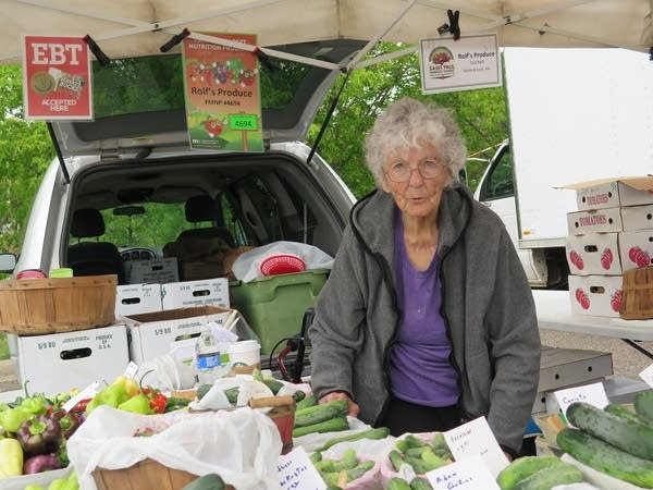 A woman sells vegetables at a farmer's market. 