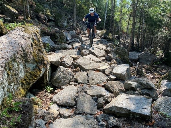 A person rides down a rocky mountain bike trail. 