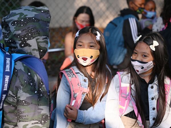 Students and parents arrive masked for the first day of the school year at Grant Elementary School in Los Angeles on Aug. 16. The reopening of schools has raised hope some parents may return to the labor force.