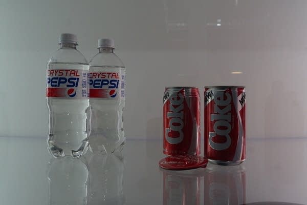 bottles of crystal pepsi next to cans of new coke