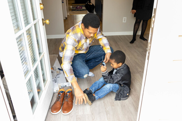 Latroun Epps helps his son, Israel Epps, put on his shoes before they play in their backyard at their Griffin, Ga., home.