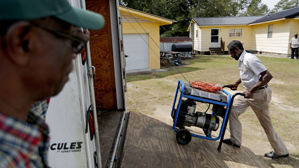 As Hurricane Florence approaches in 2018, Stoney Williamson unloads a portable generator for his brother-in-law as Harry Campbell (left) looks on in Nichols, South Carolina.