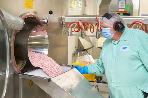 A lab technician at a Pfizer factory inspects Paxlovid tablets as they move through the manufacturing process.