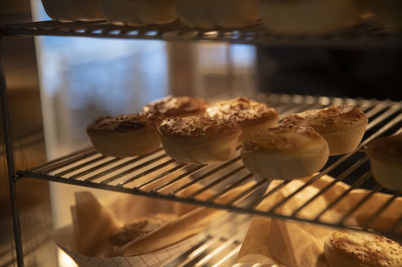 Six small, golden-brown hand hand pies sit on a rack in a warming oven.