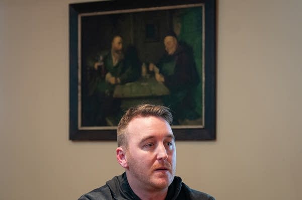A man stands beneath a painting.