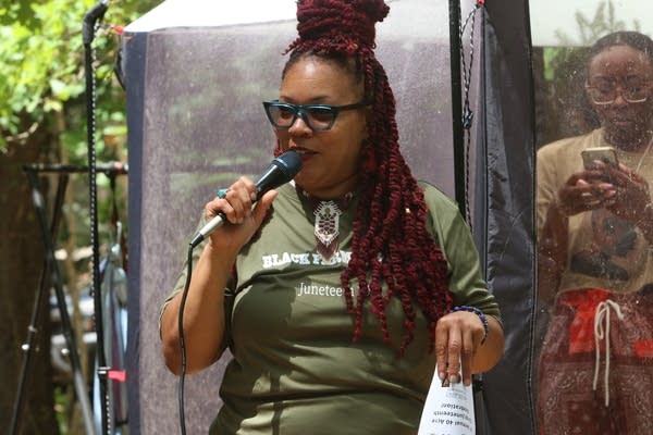 A woman speaks into a microphone outside.