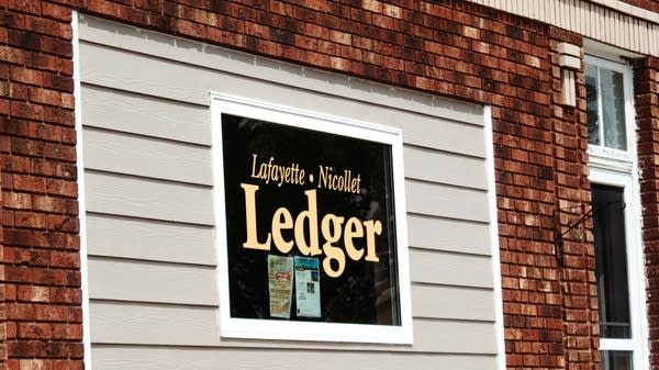 A window of the business says "Lafayette-Nicollet Ledger."