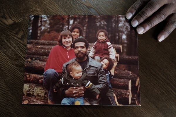 A person holds an old photo of a family.