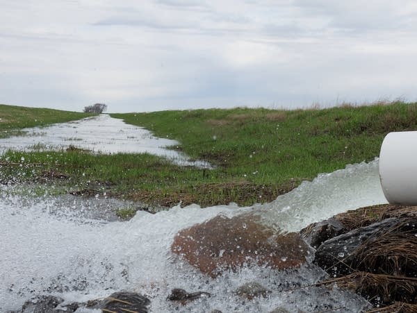 water rushes from a pipe into a ditch
