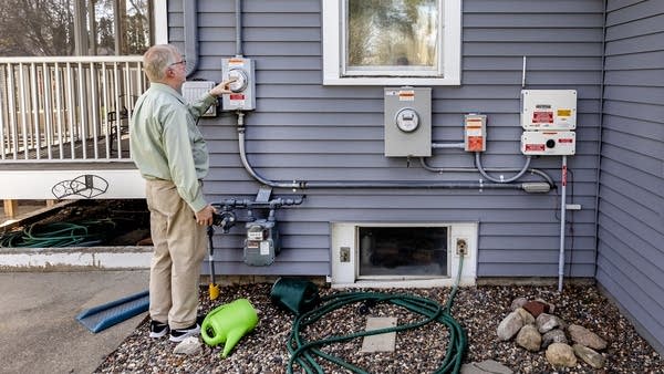 A man stands outside a house with electric equipment.