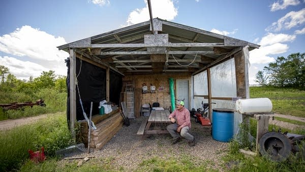 A man looks at the makeshift house in his field