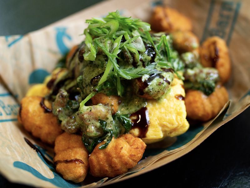 Fried gnocchi topped with scrambled eggs, sauce, and greens. 
