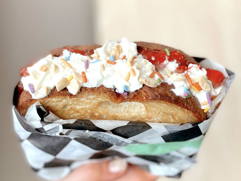A grilled sandwich made with white bread, whipped cream, strawberries, and sprinkles. 