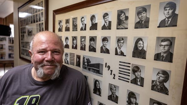 A man poses in front of old school photos