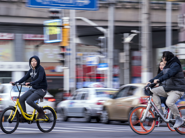 People in Shanghai riding Ofo (L) and Mobike bikeshares.