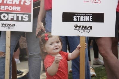 Toddler holds sign at nurses strike