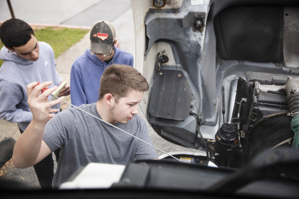 The students in the trucking class take their time going through the steps of a pre-trip inspection, checking out the truck from front to back and under the hood.
