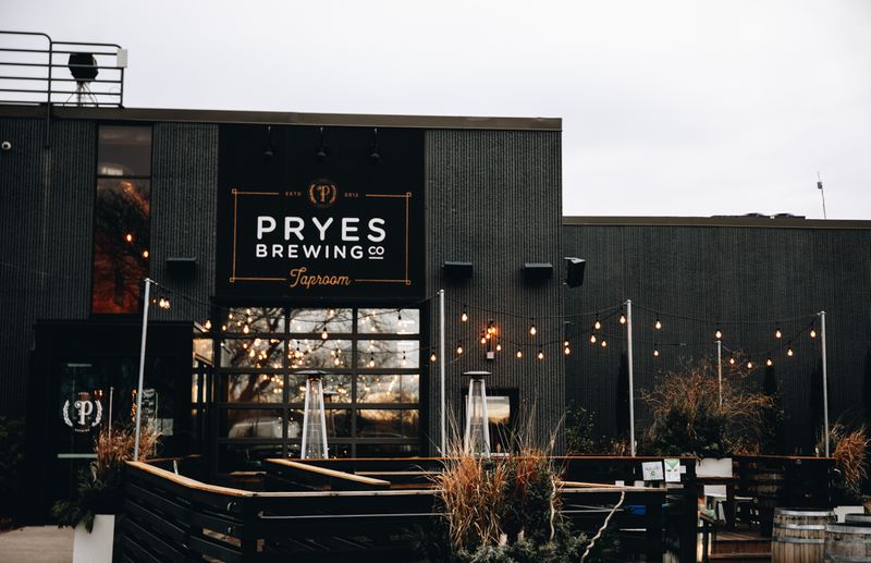 The experience of Pryes Taproom, a black building with seating and string lights in the foreground. 