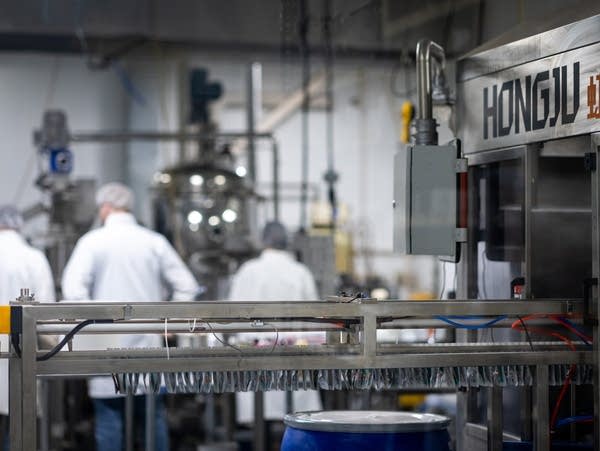 A stainless steel machine holds a production line of gummy packages