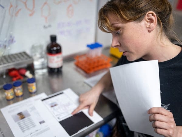 A woman holds a piece of paper and points at lab test results 