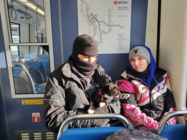 Two people on a train with a cat