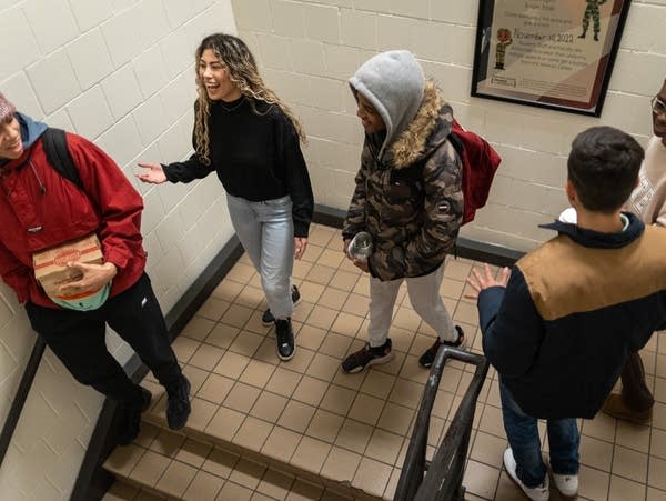 Five students walk down a staircase and chat