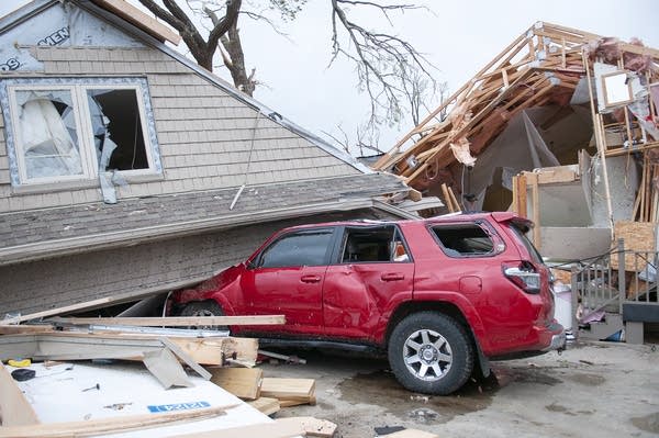 A car is seen crushed by a house.