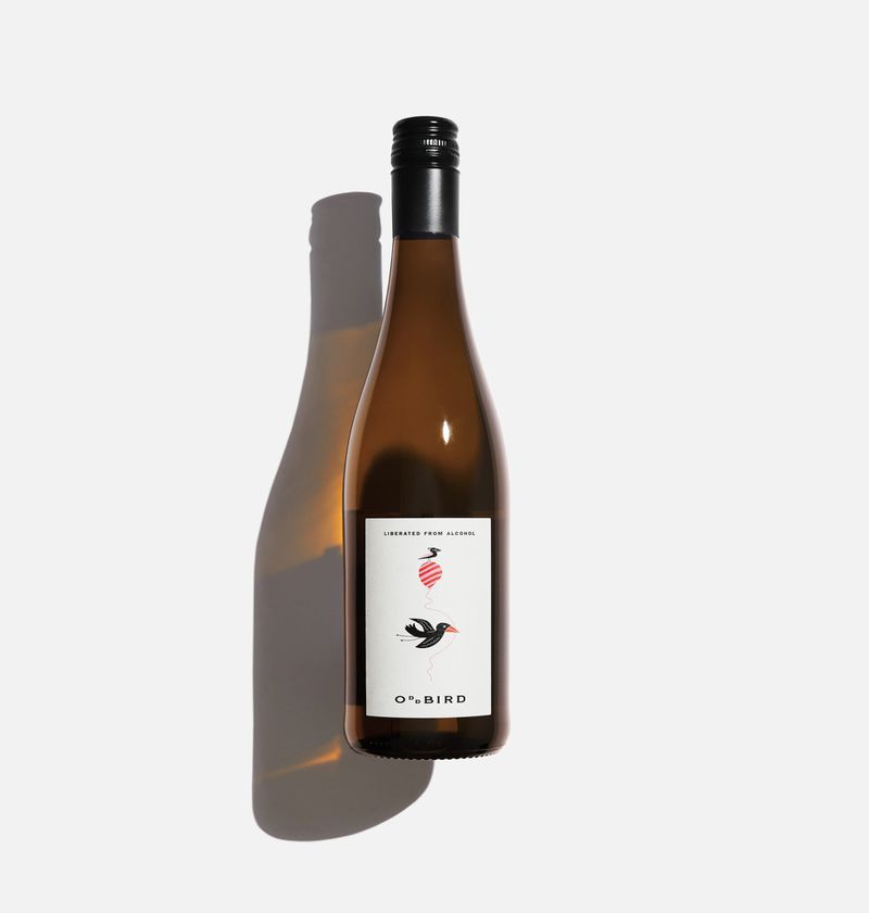 A bottle of white wine on a white background with a white label that says “Oddbird” and has a graphic of a small black bird. 