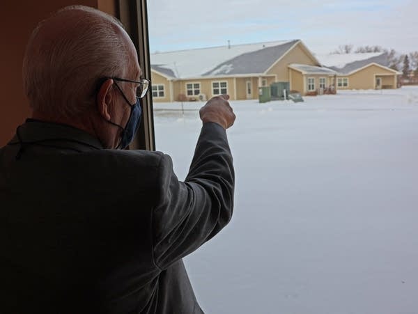 a man points out a window at a snowy field