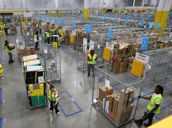 Workers move carts filled with packages at an Amazon delivery station on Nov. 28 in Alpharetta, Ga.