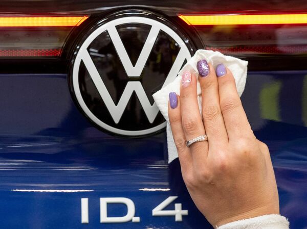 An employee cleans a VW logo on a vehicle at the assembly line for the Volkswagen ID.4 in the production site of Emden, northern Germany, on May 20, 2022. Some ID.4s will qualify for the tax credit – but not all.