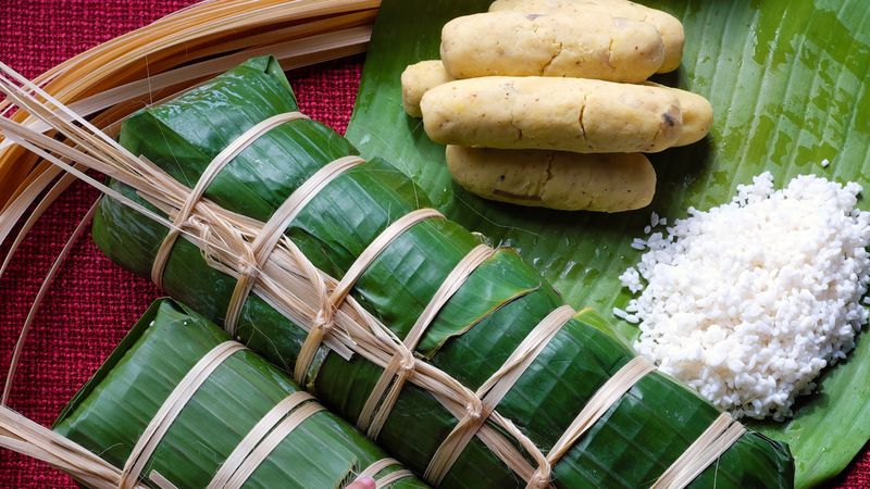 Cylindrical rice cakes wrapped in banana leaves. 