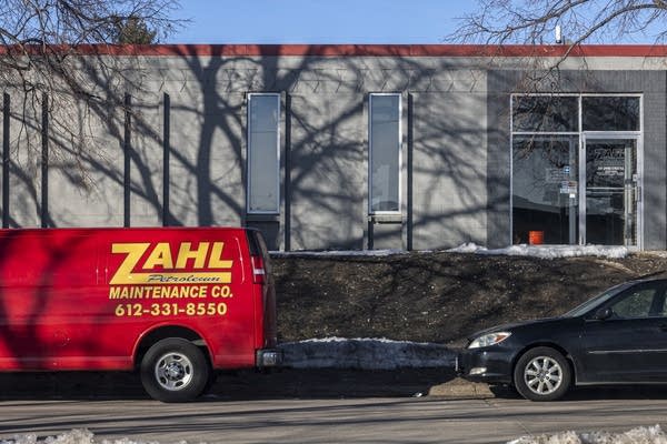 An exterior photo of a building with a red van outside