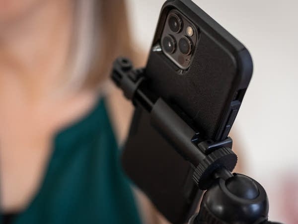 A woman uses a handheld stabilizer and smartphone to record a video