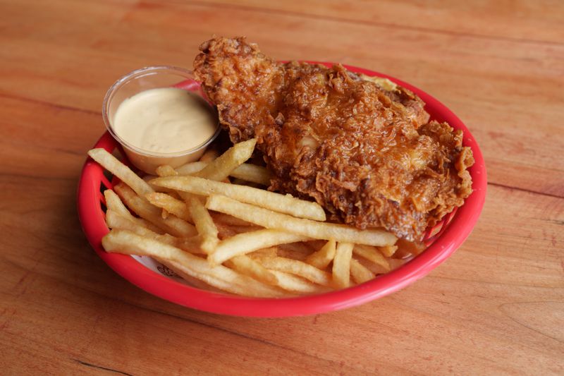 Fried chicken and french fries with a small dish of sauce.