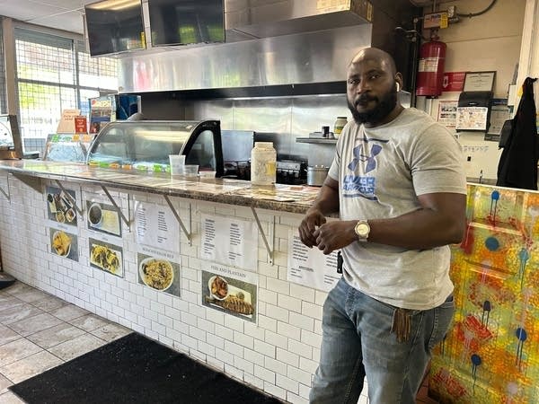a Black man stands in front of a restaurant bar