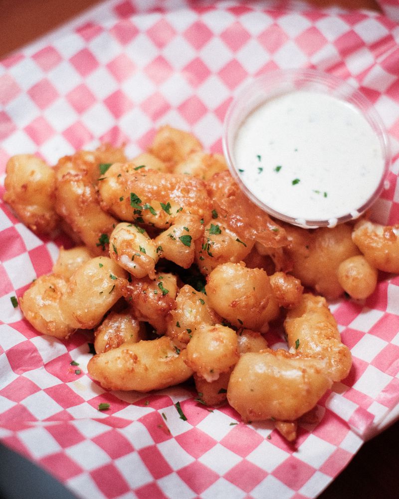 Cheese curds and ranch on red and white checked paper. 