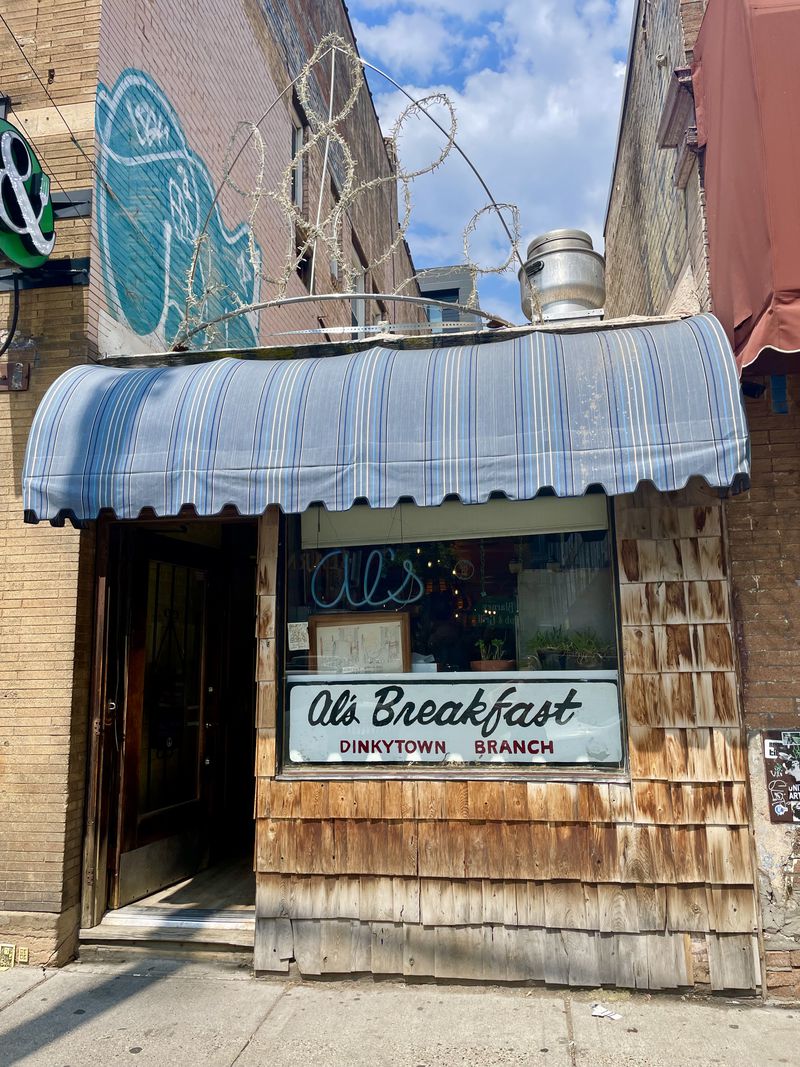 The exterior of a restaurant with a blue awning and sign that says “Al’s Breakfast.”